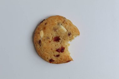 Beyaz arka planda izole edilmiş badem ve böğürtlen kesikli ısırılmış beyaz çikolatalı kurabiye.