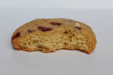 Beyaz arka planda izole edilmiş badem ve böğürtlen kesikli ısırılmış beyaz çikolatalı kurabiye.