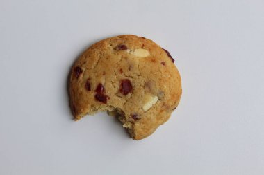 Beyaz arka planda izole edilmiş badem ve böğürtlen kesikli ısırılmış beyaz çikolatalı kurabiye.