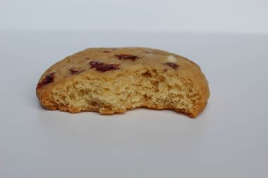 Beyaz arka planda izole edilmiş badem ve böğürtlen kesikli ısırılmış beyaz çikolatalı kurabiye.