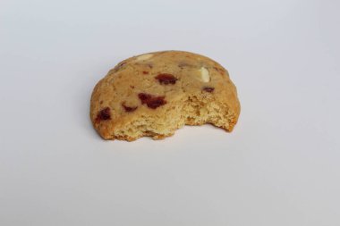 Beyaz arka planda izole edilmiş badem ve böğürtlen kesikli ısırılmış beyaz çikolatalı kurabiye.