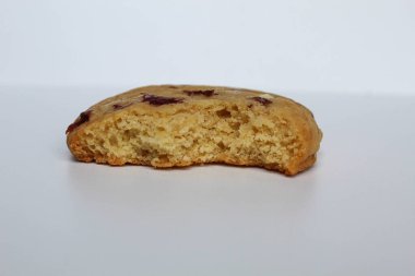 Beyaz arka planda izole edilmiş badem ve böğürtlen kesikli ısırılmış beyaz çikolatalı kurabiye.