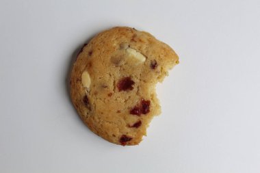 Beyaz arka planda izole edilmiş badem ve böğürtlen kesikli ısırılmış beyaz çikolatalı kurabiye.