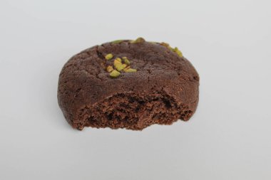 Isırılmış çikolatalı yumuşak kurabiye, yeşil fıstıklı, beyaz arka planda izole edilmiş.