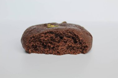 Isırılmış çikolatalı yumuşak kurabiye, yeşil fıstıklı, beyaz arka planda izole edilmiş.