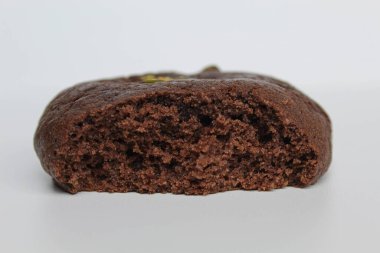 Isırılmış çikolatalı yumuşak kurabiye, yeşil fıstıklı, beyaz arka planda izole edilmiş.