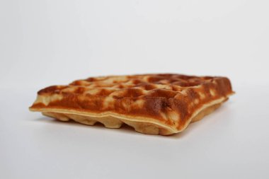 Bir sade kare waffle keki, yanmış, beyaz arka planda izole edilmiş.