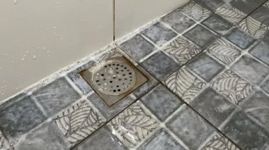 Su ve köpük banyodaki döşeme kapağına akıyor.