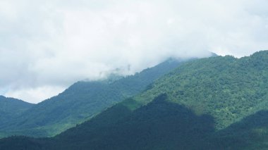 Güzel dağlar bulutlu gökyüzü ve aralarında vadi ile görünür.