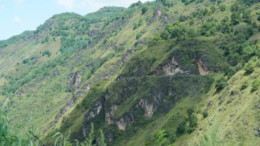 Güzel dağlar bulutlu gökyüzü ve aralarında vadi ile görünür.