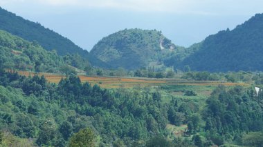 Güzel dağlar bulutlu gökyüzü ve aralarında vadi ile görünür.