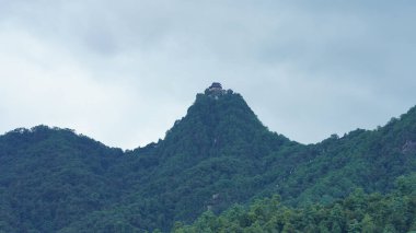Güzel dağlar bulutlu gökyüzü ve aralarında vadi ile görünür.