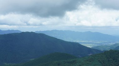 Güzel dağlar bulutlu gökyüzü ve aralarında vadi ile görünür.