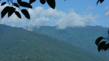 Güzel dağlar bulutlu gökyüzü ve aralarında vadi ile görünür.