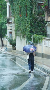 Yağmurlu günde şemsiyeyle yürüyen insanlar