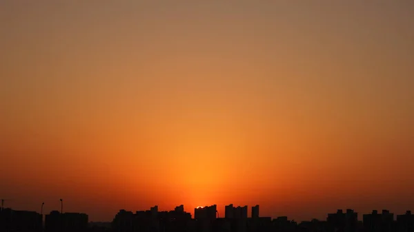 以建筑物的轮廓和橙色的天空为背景的美丽的日落景观 — 图库照片