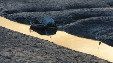 Deniz kıyısı manzarası gelgitle aşağı ve günbatımının arka planıyla