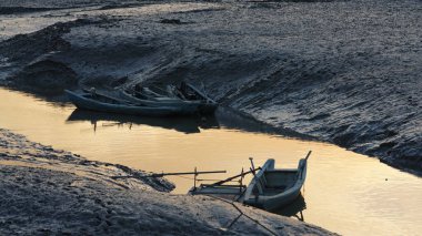 Deniz kıyısı manzarası gelgitle aşağı ve günbatımının arka planıyla