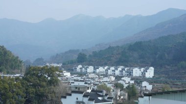 Çin 'in güneyinde eski köy ve dağlarla güzel bir kır manzarası.