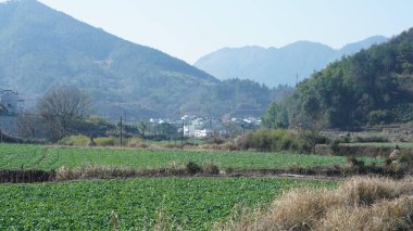 Çin 'in güneyinde eski köy ve dağlarla güzel bir kır manzarası.