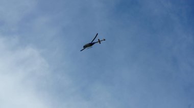 Arka planda mavi gökyüzü ile uçan bir helikopter
