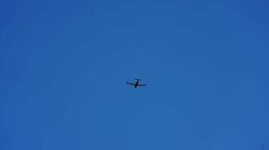 Güneşli bir günde açık mavi gökyüzünde uçan bir uçak.