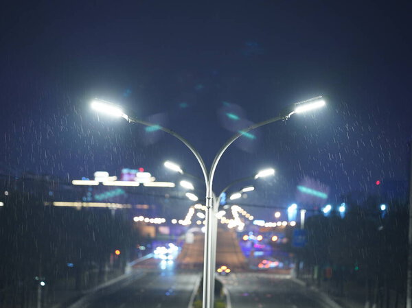 The road view with the lights on in the city in the rainy evening
