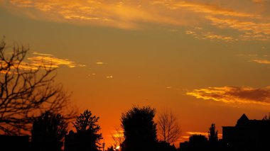 Gün batımı manzarası, şehirde siluet ve sarı gökyüzü.