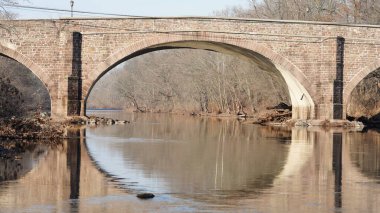 Amerika 'nın kırsal kesiminde nehrin üzerinden geçen eski bir kemerli köprü.