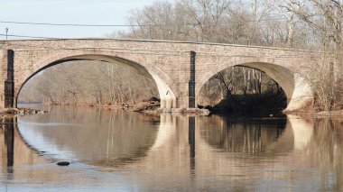 Amerika 'nın kırsal kesiminde nehrin üzerinden geçen eski bir kemerli köprü.