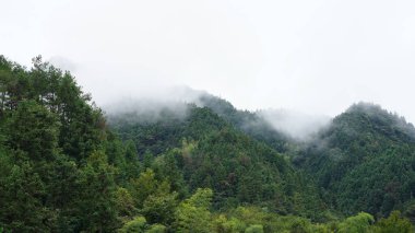 Yeşil ormanlı güzel dağlar ve yağmurlu günlerde arka planda kalan küçük köyler.