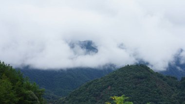 Yeşil ormanlı güzel dağlar ve yağmurlu günlerde arka planda kalan küçük köyler.