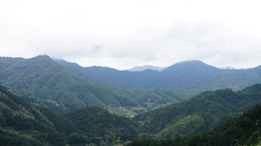 Yeşil ormanlı güzel dağlar ve yağmurlu günlerde arka planda kalan küçük köyler.