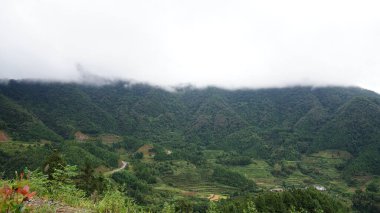 Yeşil ormanlı güzel dağlar ve yağmurlu günlerde arka planda kalan küçük köyler.