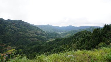 Yeşil ormanlı güzel dağlar ve yağmurlu günlerde arka planda kalan küçük köyler.