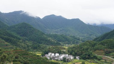 Yeşil ormanlı güzel dağlar ve yağmurlu günlerde arka planda kalan küçük köyler.