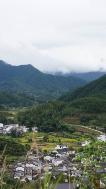 Yeşil ormanlı güzel dağlar ve yağmurlu günlerde arka planda kalan küçük köyler.