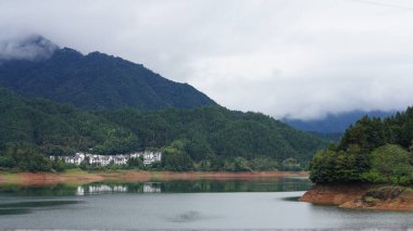 Yeşil ormanı olan güzel dağlar ve Çin kırsalının arka planında küçük bir köy.