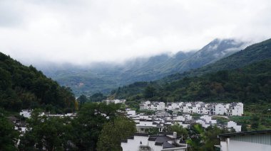 Yeşil ormanı olan güzel dağlar ve Çin kırsalının arka planında küçük bir köy.