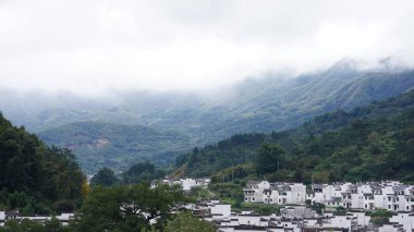 Yeşil ormanı olan güzel dağlar ve Çin kırsalının arka planında küçük bir köy.