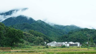 Yeşil ormanı olan güzel dağlar ve Çin kırsalının arka planında küçük bir köy.
