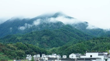 Yeşil ormanı olan güzel dağlar ve Çin kırsalının arka planında küçük bir köy.