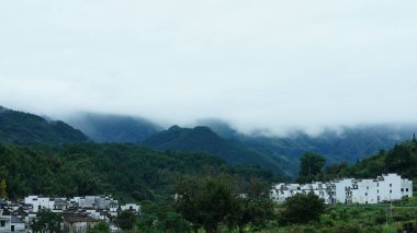 Yeşil ormanı olan güzel dağlar ve Çin kırsalının arka planında küçük bir köy.