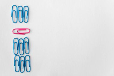 Bu kavramsal fotoğraf, grubun üzerine belirgin bir şekilde yerleştirilmiş tek bir pembe ataç ile yapılandırılmış bir desen içinde düzenlenmiş mavi ataç koleksiyonunu içerir. Mavi arasındaki kontrastı.