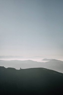 A peaceful morning view of mist-covered valleys and rolling green hills under a soft sky, capturing the serene beauty of the countryside. clipart