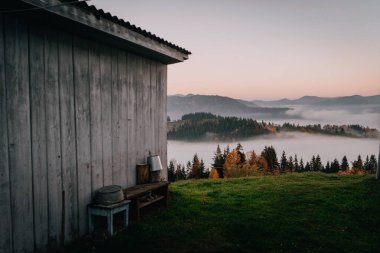 Sakin bir ahşap kulübe, sislerle kaplı bir vadiye bakan çimenli bir tepenin kenarında oturur ve şafak vakti ormanlarla kaplı dağlar doğanın huzur dolu özünü yakalar..