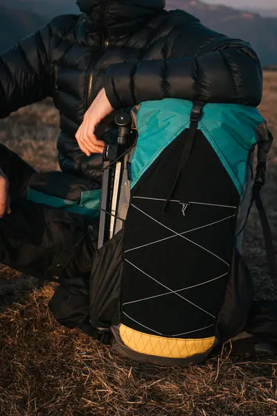 Bir yürüyüşçü bir dağda oturur ve yolculuklarının bir sonraki aşamasına hazırlanırken sırt çantasının içindekileri dikkatlice düzenler. Akşam ışığı sahneye sıcak bir parıltı saçar..