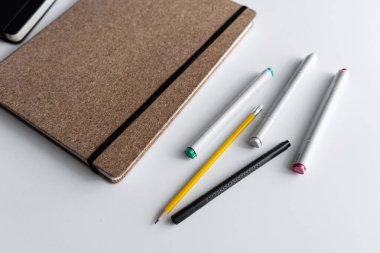 Beyaz bir yüzeyde iki defter, bir kalem ve bir kalemden oluşan minimalist bir düzenleme. Görüntü üretkenlik, günlük veya organizasyon temaları için basit ve temiz bir kompozisyon içerir..