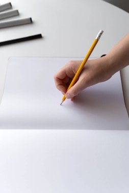 Bir kadının eli boş bir sayfaya kalem tutarken yakın plan çekimi yaratıcılığı, yeni bir başlangıcı ya da yeni bir başlangıcı simgeler. Yazma, planlama veya yaratıcılıkla ilgili kavramlar için ideal.