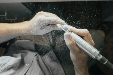 Hassas bir aletle bir tahta parçasını ustalıkla oyan detaylı bir yakın çekim. İnce ahşap talaşları ve toz çalışma alanını sarar. Karmaşık işçiliği gösterir ve detaylara odaklanır..